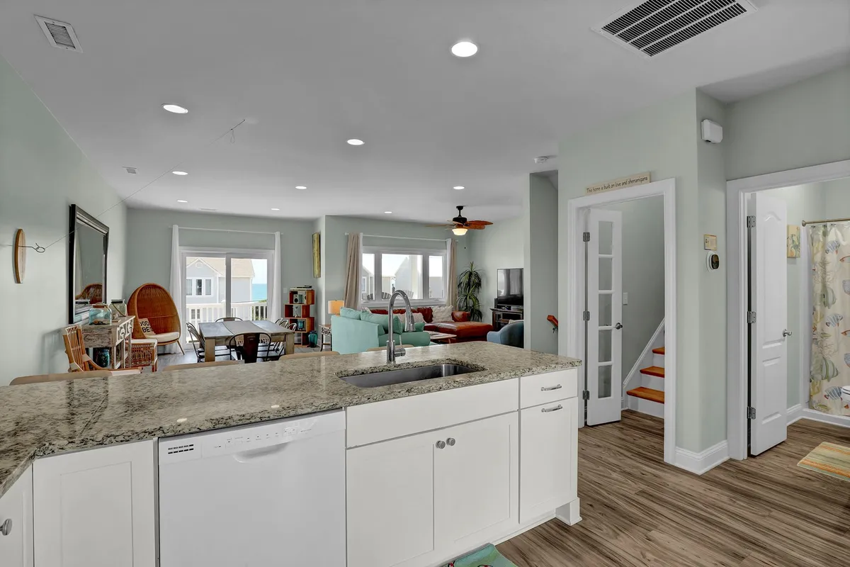 An open-plan interior that seamlessly connects the kitchen island with the living area and staircase. The design fosters easy flow between food preparation, entertaining, and relaxing, reinforcing the kitchen as the home's vibrant heart.