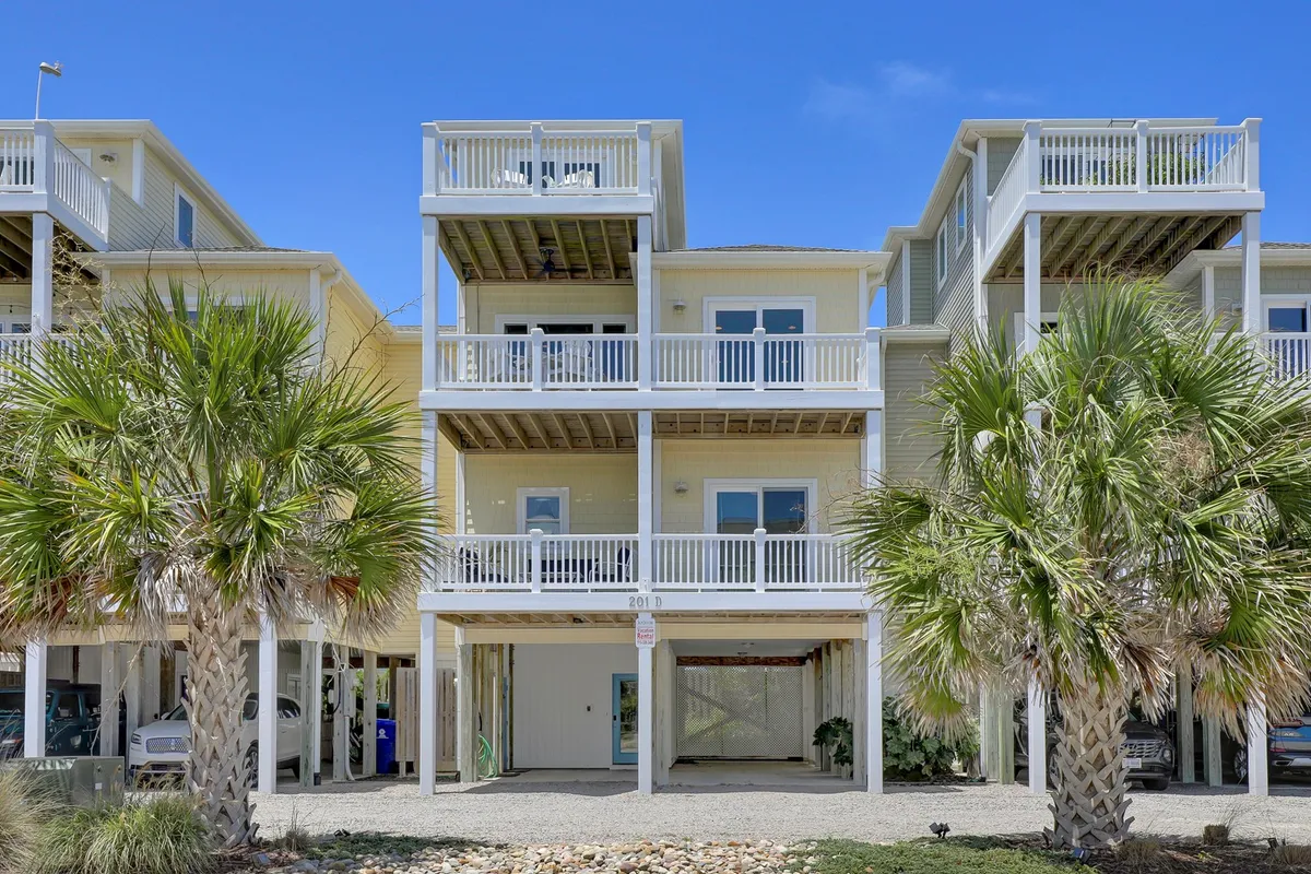 The image captures the inviting exterior of a spacious single-family beach home, framed by swaying palm trees, wide balconies perfect for relaxing, and a welcoming front porch ideal for gathering. The scene evokes leisurely mornings with coffee on the balcony, ocean breezes, and evenings spent barbecuing with friends or family.