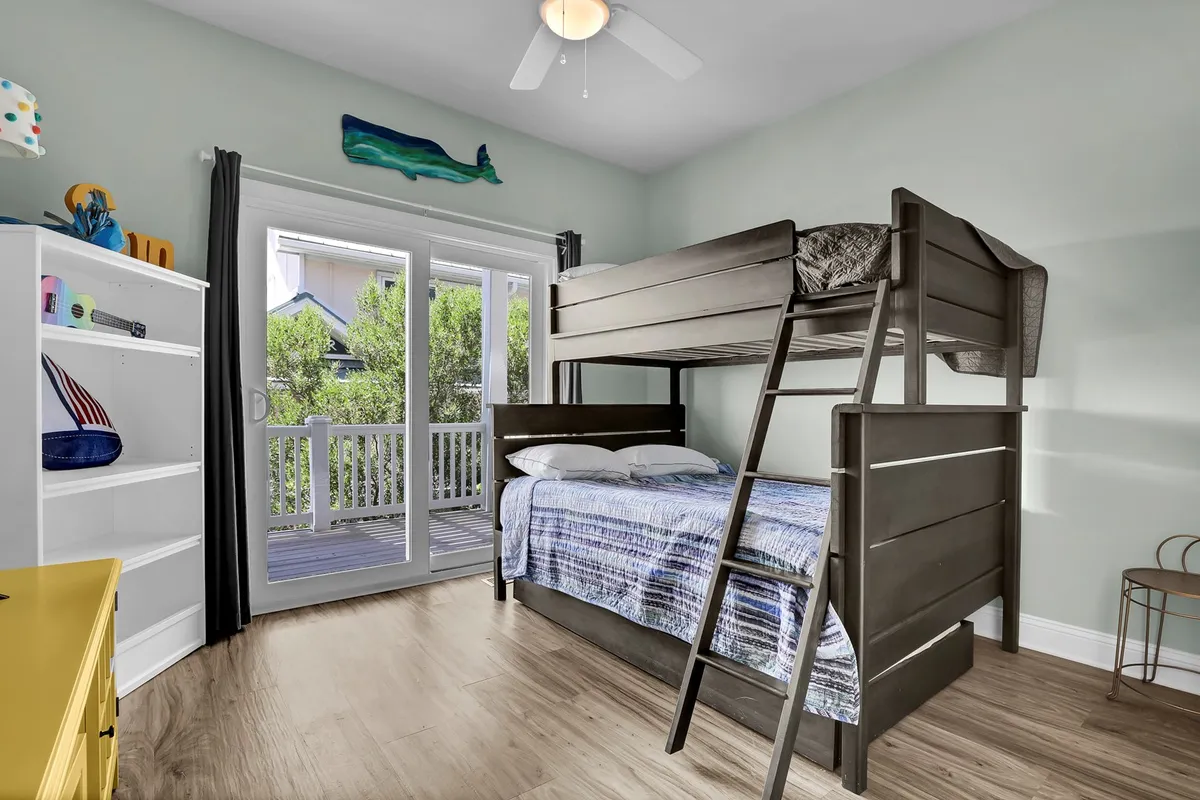 A playful bedroom equipped with a twin-over-full bunk bed, a colorful dresser, bookshelf, and sliding doors. The décor is lively, making it ideal for kids or families sharing a room.